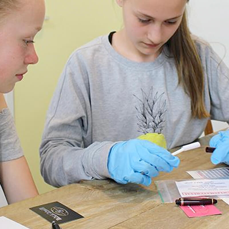 twee meisjes die binnen bewijsmateriaal onderzoeken met handschoentjes voor een misdaadspel