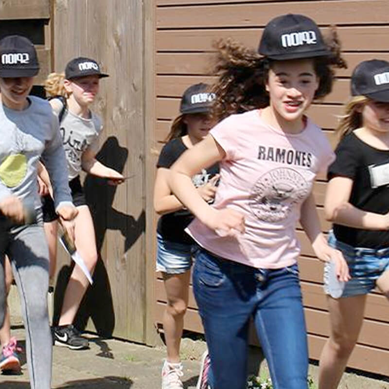 foto van een aantal kinderen die enthousiast buiten rennen tijdens het spelen van een misdaadspel met caps van noi92