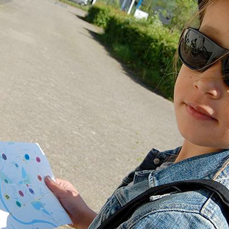 foto van een meisje buiten met een plattegrond in haar hand waar de aanwijzingen verstopt zijn voor een misdaadspel