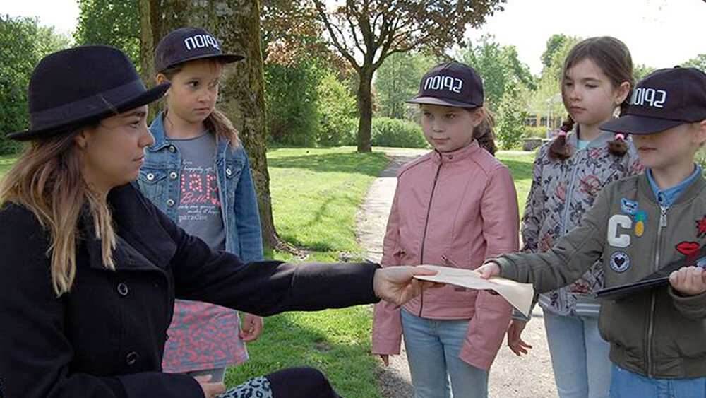 foto van kinderen buiten in het park die een belangrijke envelop krijgen van een geheim agent