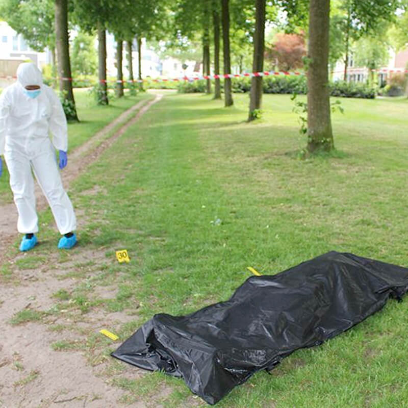 foto in een park van een plaat delict door een forensisch onderzoeker met een lichaam in een lijkschouwingszak voor een moordspel thuis